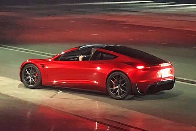 A gentleman driving a red 2020 Tesla Roadster