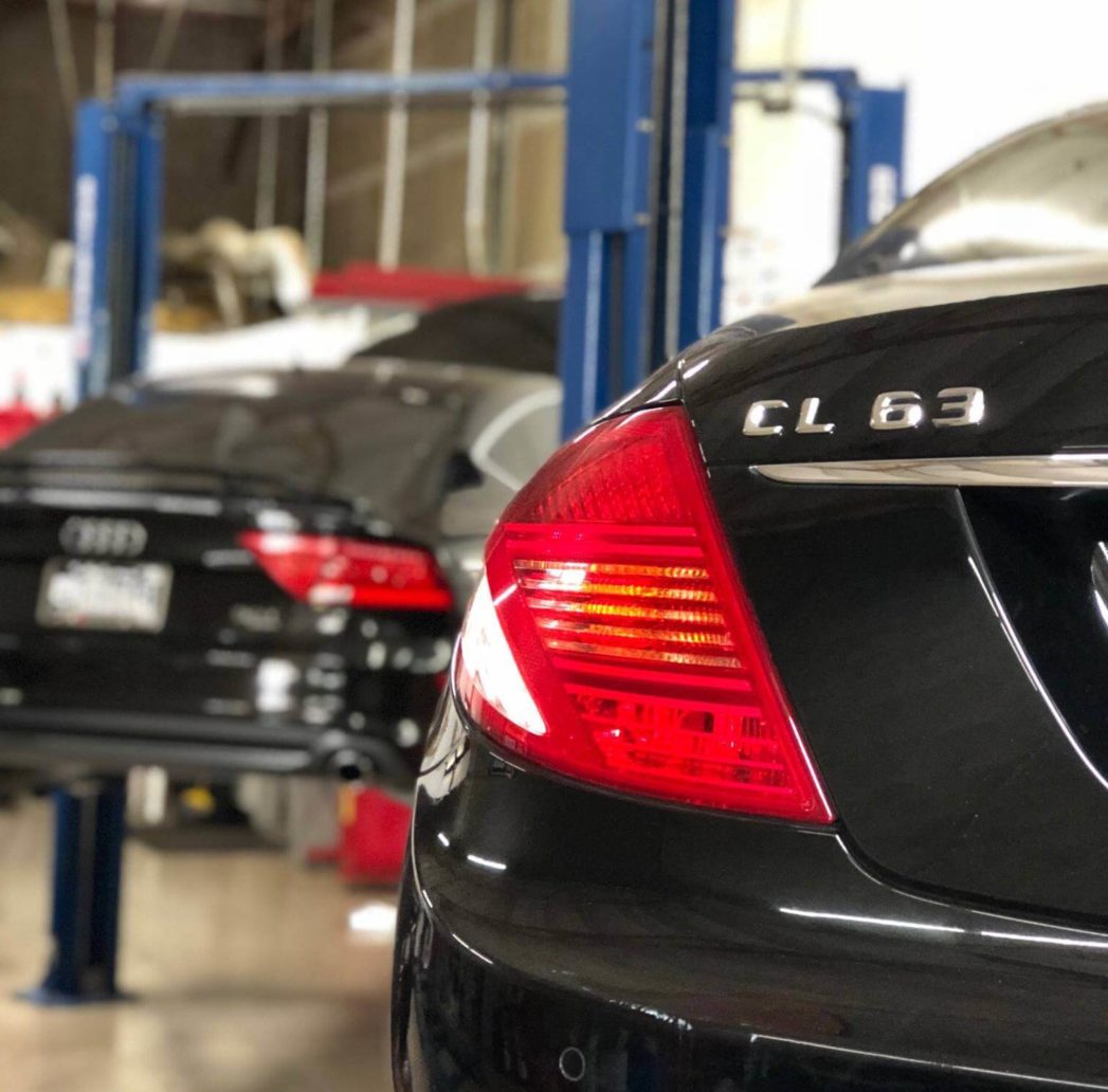 A black CL63 with an Audi on a car lift out of focus; Mercedes