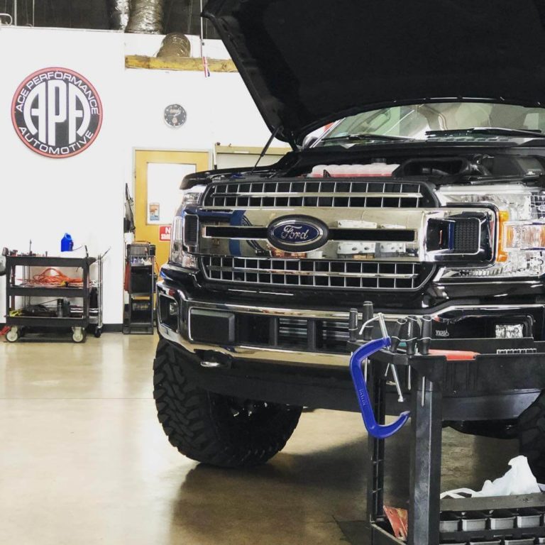 A black Ford F250 with the hood raised inside of the Ace Performance Automotive building; Powerstroke