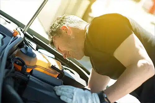 Does Car Maintenance Really Pay Off In The Long Run? | APA Total Care in Queen Creek, AZ. Image of a mechanic performing checking and maintaining a car engine under the hood.