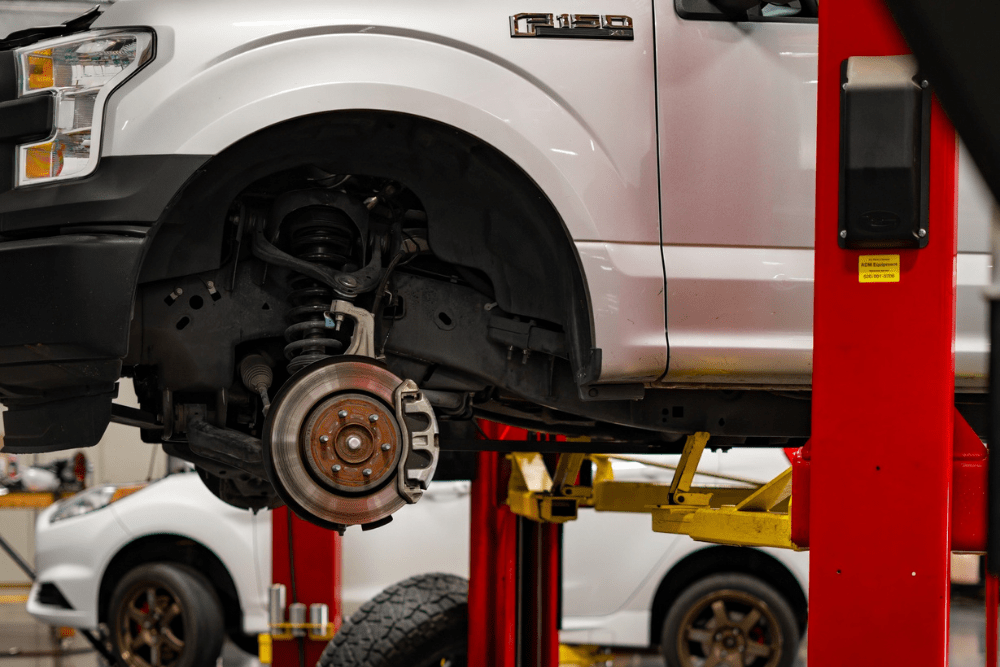 Brake inspection, auto repair in Queen Creek, AZ by APA Total Car Care. Image of a truck lifted with the wheel removed, exposing the brake rotor and caliper during service. Highlighting APA Total Car Care’s commitment to safe braking performance and reliable vehicle maintenance.